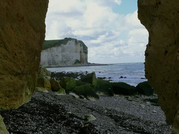 2007.09 - 'A see-through view between two ocher-colored rocks', on the steep cliffs on the shore of Petit-Dalle in Normandy France under a blue-white sky; French landscape photography, Fons Heijnsbroe...