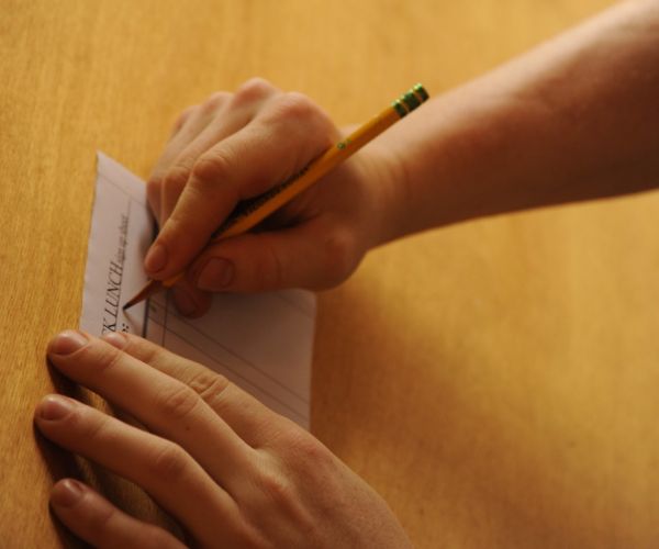 A volunteer making out the lunch request, pencil and paper form, hands, wood, kitchen, Breitenbush Hot Springs, Breitenbush, Marion County, Oregon, USA