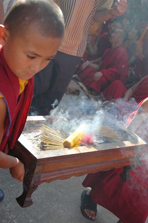 A young monk carrying lit incense out of the shrine, a cloud of incense, Bodhisattva Day, Tharlam Monastery of Tibetan Buddhism, Kathmandu, Nepal