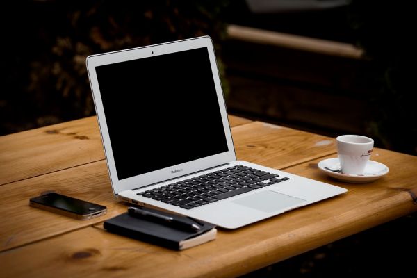 Apple Macbook Air on Wood Tabletop with Espresso Cup, Notepad, Pen, and iPhone