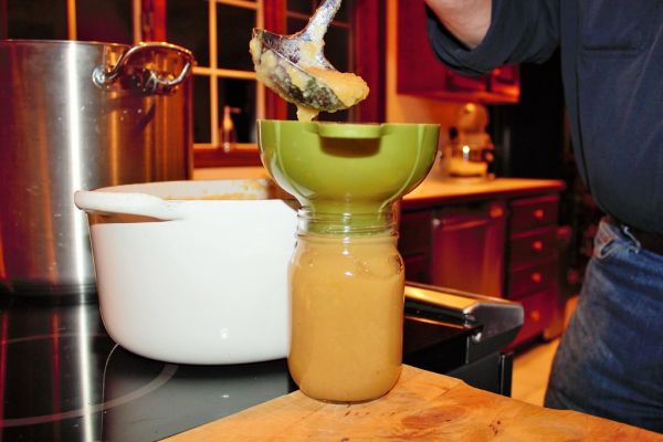 Applesauce being ladled into canning jar