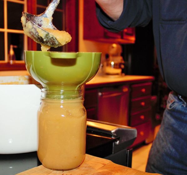 Applesauce being ladled into mason jar