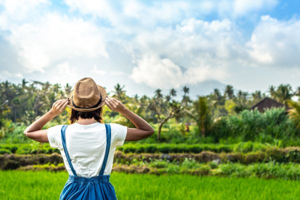 Closeup portrait of happy woman tourist with straw hat on a mountain background. Volcano Agung, Bali island.