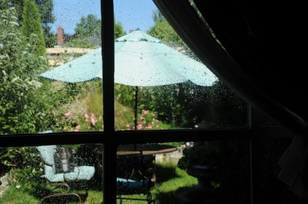 Cooling down on a hot summer day, water drops on the window, open curtain, blue umbrella, patio table, chairs, Japanese lantern, lawn, garden, Seattle, Washington, USA