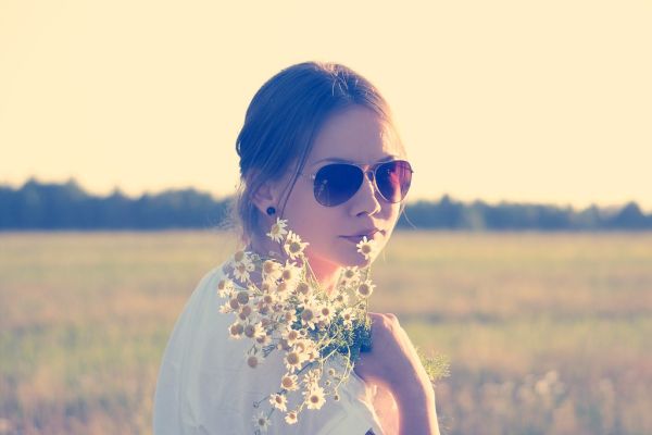 Female in Sunglasses Holding White Flowers