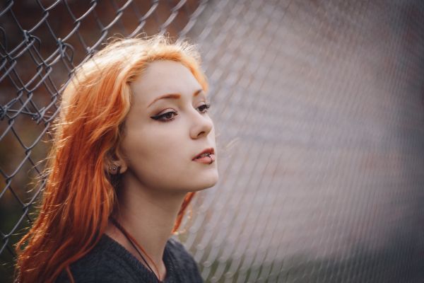 Girl leaning against a net fence