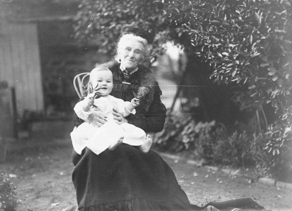 GN00432 Grandmother with baby on knee sitting in garden