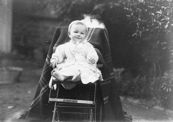 GN00434 Baby sitting in push chair in garden