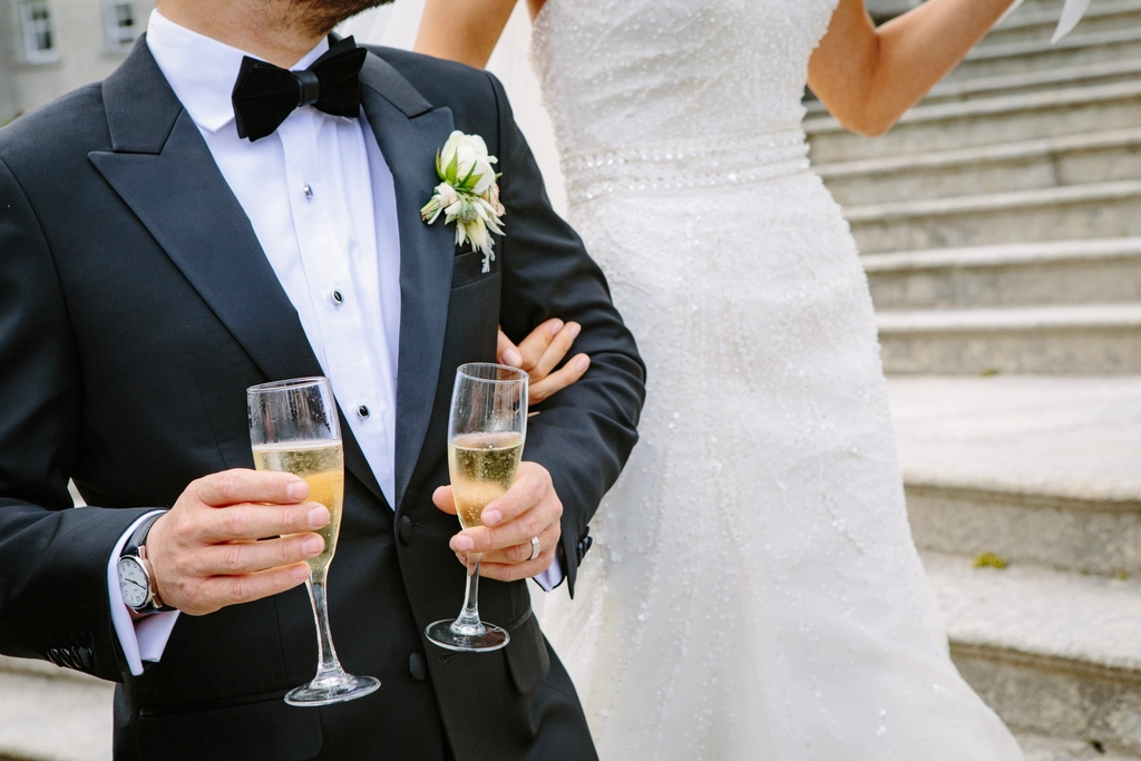 groom holding two champagne glasses