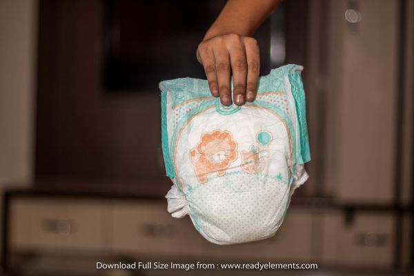 Hand holding used baby diaper