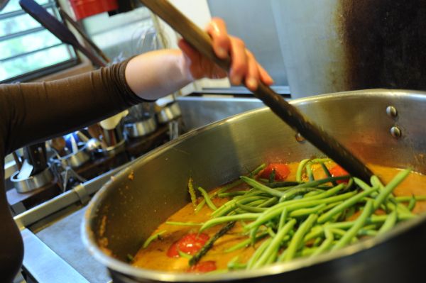 Making a big pot of vegetarian green bean soup, wooden paddle spoon, young woman in a brown shirt, pot, kitchen, Breitenbush Hot Springs, Breitenbush, Oregon, USA