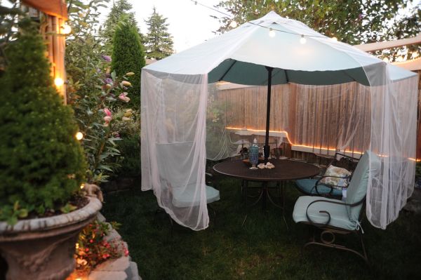 Mosquito netting over the blue green umbrella, patio set, pink lilies just blooming, evening, lights, A Garden for the Buddha, Seattle, Washington, USA