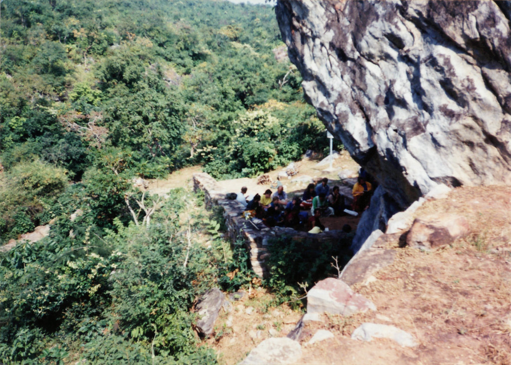 Seattle Tibetan Buddhist sangha sit, reciting prayers, lead by His Holiness Dagchen Sakya Rinpoche, on pilgrimage, in the shade of the cave under Vulture Peak, Madhya Pradesh, India, 1993