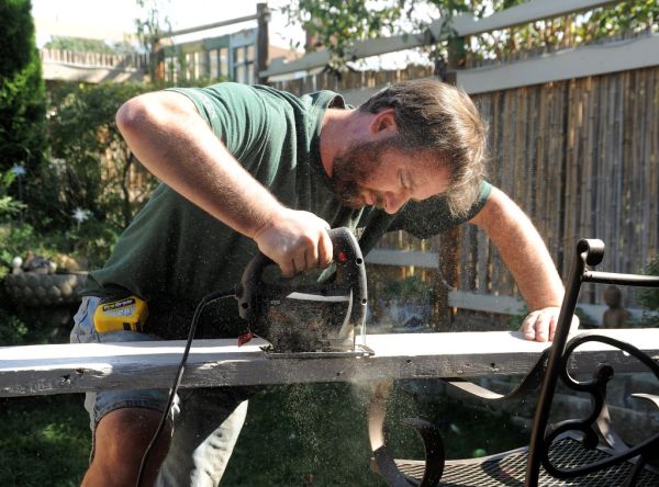 Stephen cutting decorative detail, armchair carpentry, jigsaw, tape measure, sunny day, lotus fountain, A Garden for the Buddha, Seattle, Washington, USA