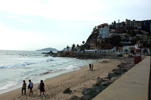 Strolling down the beach with surf boards, hanging out under an umbrella, South Mazatlan beach in the afternoon, beyond the seawall, Mexico