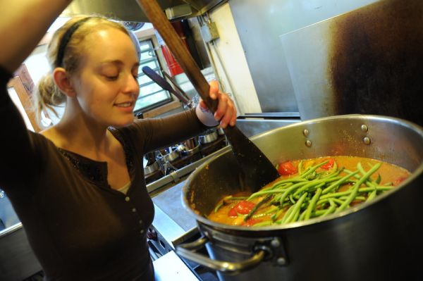 The cook's smile, cooking vegetarian green bean soup, big wooden paddle spoon, young woman in a brown shirt, pot, kitchen, Breitenbush Hot Springs, Breitenbush, Oregon, USA