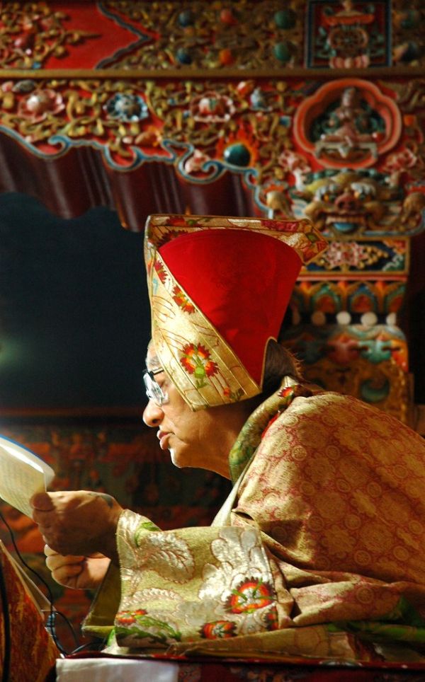 Transmission on the Triple Tantra: His Holiness Jigdal Dagchen Sakya reading a pecha, wearing formal silk robes, on his teaching throne, Tharlam Monastery of Tibetan Buddhism, Boudha, Kathmandu, Nepal