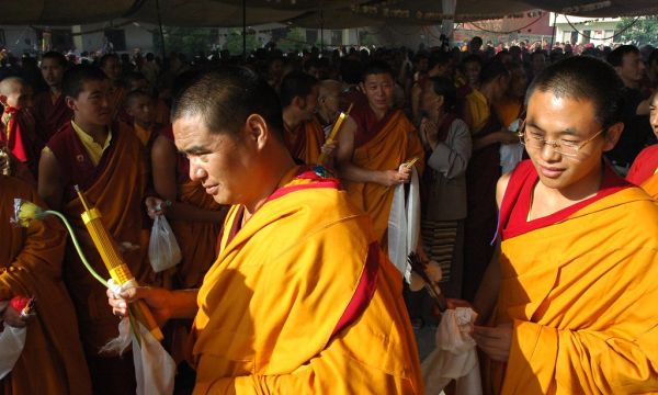 Wearing sanghati - bright orange robes - two lamas in the Sakya Lamdre Bodhisattva Day procession, a monk carries flower, incense, katag and mala, offerings to the Buddha, Tharlam Monastery courtyard,...
