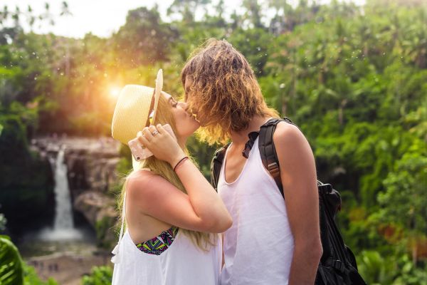 Young couple kissing on a waterfall background