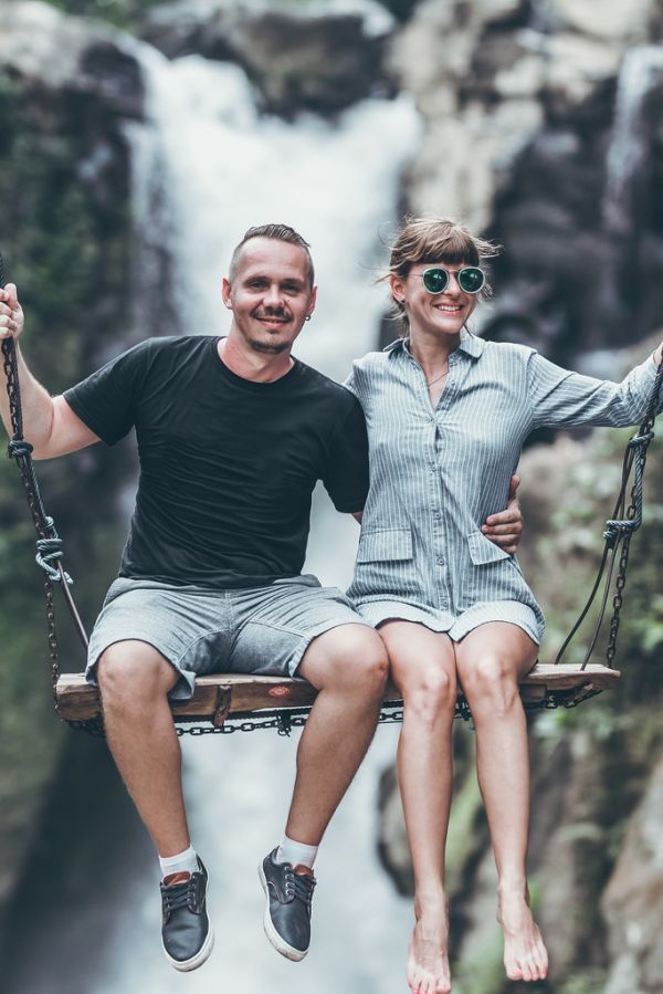 Young honeymoon couple swings in the jungle near the waterfall, Bali island, Indonesia. Ubud.