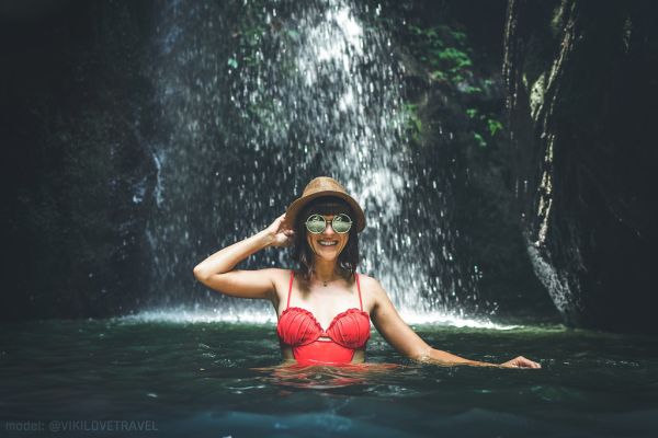 Young woman tourist in the deep jungle with waterfall. Real adventure concept. Bali island.