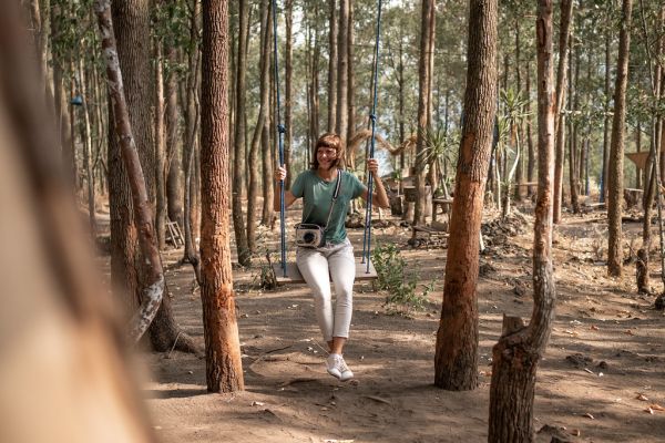 Young woman on the swing in the forest. Bali island.